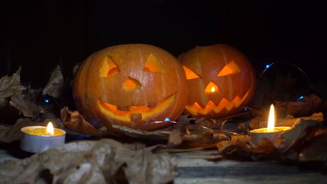 Halloween, two pumpkins with a scary luminous face inside, candles are burning and light is playing, changing.