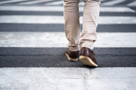 close up legs of man walking cross street in city