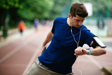 Young man checking his heart rate during work out. Young man exercising on athletics track