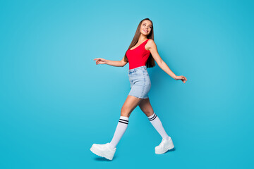 Fototapeta na wymiar Full size profile side photo of cute lovely pretty content girl walk go enjoy spring free time weekend look copyspace wear legs shoes tank-top isolated over blue color background