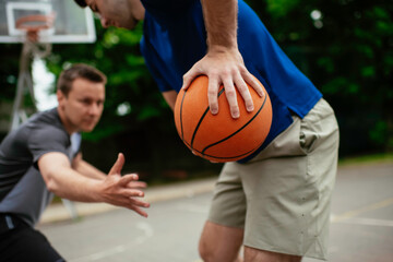 Close up of hands holding ball. Friends playing basketball in the park.