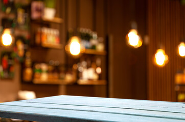 Empty wood table top on blur light gold bokeh of cafe restaurant in dark background