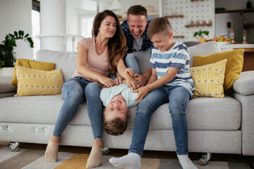 Young family enjoying at home. Happy parents with sons having fun.