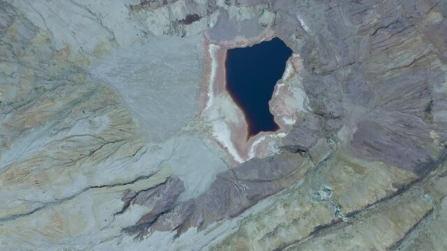 Aerial top view of pond amidst rock formation at copper quarry, drone flying forward over open-pit mine - Bisbee, Arizona
