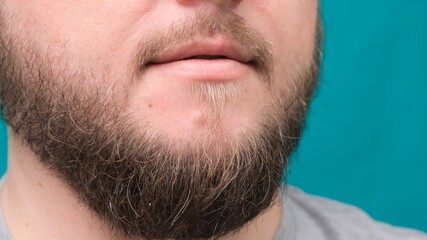 Obraz premium Close-up of male lips and bearded chin on a green background