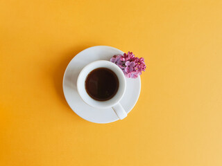 White cup with black coffee on a bright yellow background. View from above. Good morning and the...