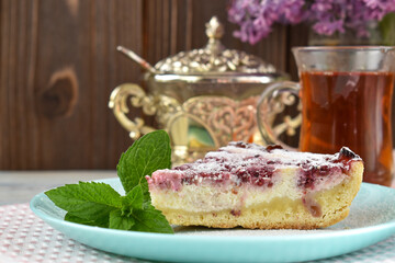 Sliced piece of cottage cheese cake with raspberries on a background of sugar bowl and tea. Summer breakfast.