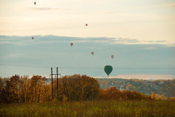 Colorful big hot air  balloons flying against the cloudy sky  in the countryside on a fall evening