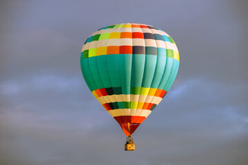 Fototapeta na wymiar Colorful big hot air balloon flying against the cloudy sky