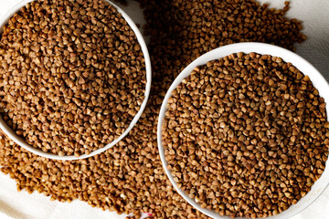 Bowl of raw uncooked buckwheat on wooden table