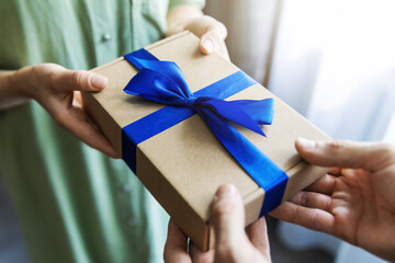 man giving gift box with blue ribbon to woman