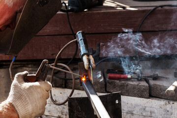 The concept of arc welding with protective metal. A man in a protective mask is engaged in arc welding of fixed iron