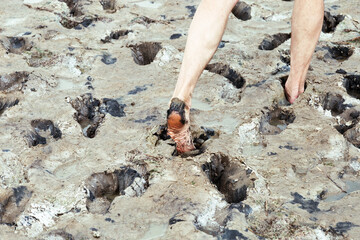 Feet sink into mud on shore of Lake Ebeyty, therapeutic mud, salt lake in Omsk region (Russia).