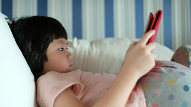 kid is addicted to tablet, little girl playing smartphone, watching cartoon
