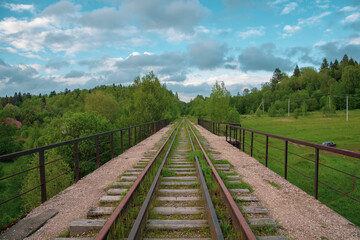 Fototapeta na wymiar An old Abandoned railway, overgrown with green grass.