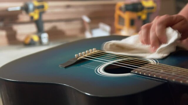 A man polishing his newly painted blue guitar.  Shines it up real nice