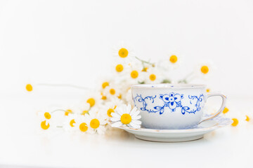 Bouquet of daisies and vintage tea cup on white background.  With copy space.
Cup of aromatic tea with a camomile flowers. Place for text. 