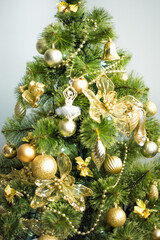 Vertical picture of green christmas tree with golden christmas decorations and yellow lights. Happy New year and merry Christmas. Selective focus
