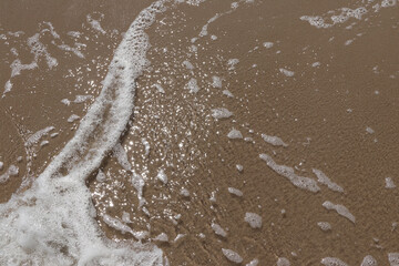 Gentle wave on sandy beach. Sun, sand and the sea to make summer holiday perfect. Sun reflexes in water and wet sand.