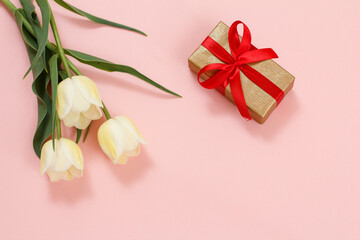 Fototapeta na wymiar Gift box with tulip flowers on a pink background.