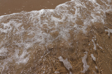 Gentle wave on sandy beach. Sun, sand and the sea to make summer holiday perfect. Sun reflexes in water and wet sand.
