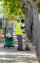 street cleaner with trash can and broom
