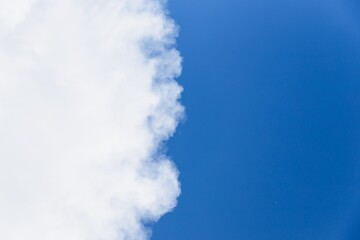 Sky background with big white cloud. Half of the blue sky, half white cloud