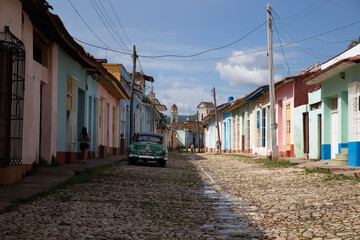 Trinidad, Cuba - October 10, 2017: Colorful streets and traditional houses of trinidad and a green old cuban car parked on a sunny day