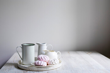 Fototapeta na wymiar A tray with mugs, milkman and pink marshmallows.