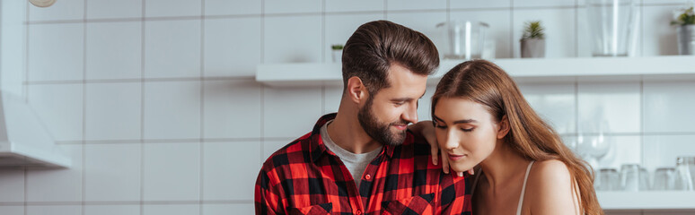 panoramic shot of happy young couple in kitchen