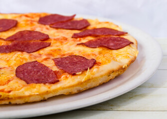 Pepperoni pizza on a white plate side view close up