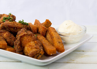 Fried chicken wings and fired bread with sauce and green olives side view close up