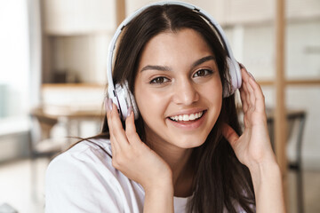 Photo of smiling beautiful woman using wireless headphone