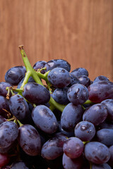fresh ripe red grapes on a wood texture surface. Ancient style, beautiful background with a branch of blue grapes. Red grape. Dark grapes