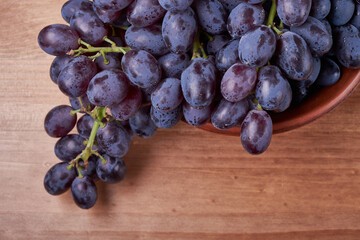Fototapeta premium fresh ripe red grapes on a wood texture surface. Ancient style, beautiful background with a branch of blue grapes. Red grape. Dark grapes
