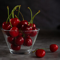 Fototapeta na wymiar Two cherries on the table and bowl full of cherries