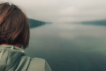 Fototapeta premium Female hiker standing on bridge and looking over lake