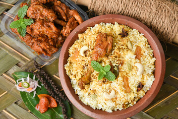 Spicy and delicious chicken biryani in traditional clay pot. Malabar biryani or Hydrabadi chicken biryani, Dum Biriyani, Chicken pulao basmati rice, herbs, raitha for Ramadan Kareem, Eid-Ul-Adha