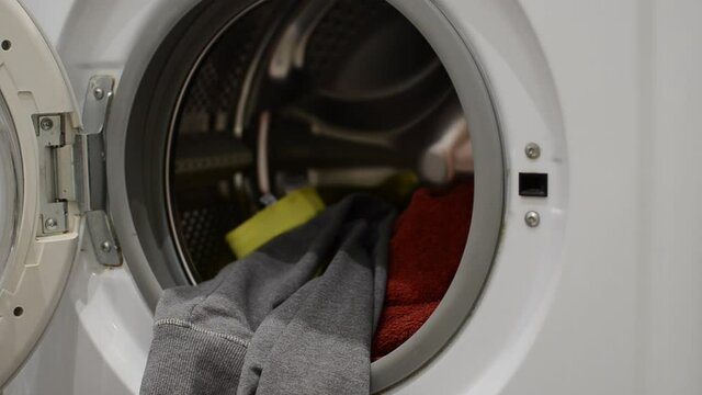 Housekeeper throws dirty clothes into the washing machine