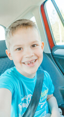 Funny cute happy child in car taking selfies and laughing. Family traveling in car