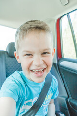 Funny cute happy child in car taking selfies and laughing. Family traveling in car