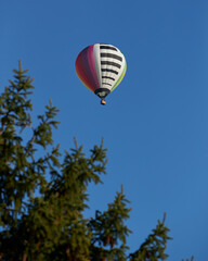Hot air balloon against blue sky with three in foreground