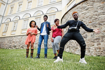 Fototapeta premium Four african friends having fun and dancing outdoors. Two black girls with guys.
