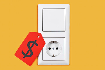 Electricity price rate concept with plug socket and light switch with red price tag on yellow wall