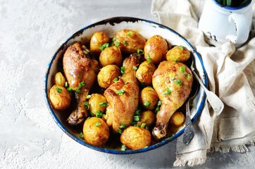 Baked chicken legs with young potatoes in a baking dish on a gray background