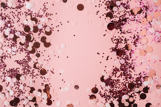 Pink celebration background with holiday sparkling confetti. Flat lay, top view