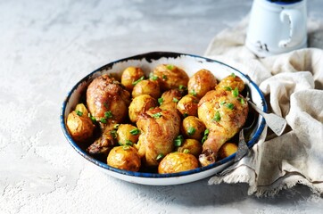 Baked chicken legs with young potatoes in a baking dish on a gray background