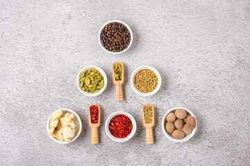 mix of aromatic spices coriander, black pepper, bergamot, dried ginger, nutmeg, paprika in white cups on gray concrete background Top view Flat lay Healthy food