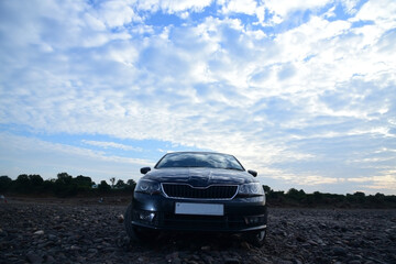 Front view of a luxury car on village road with dramatic sky