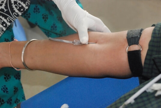 blood donation. female doctor tacking blood on man hand.